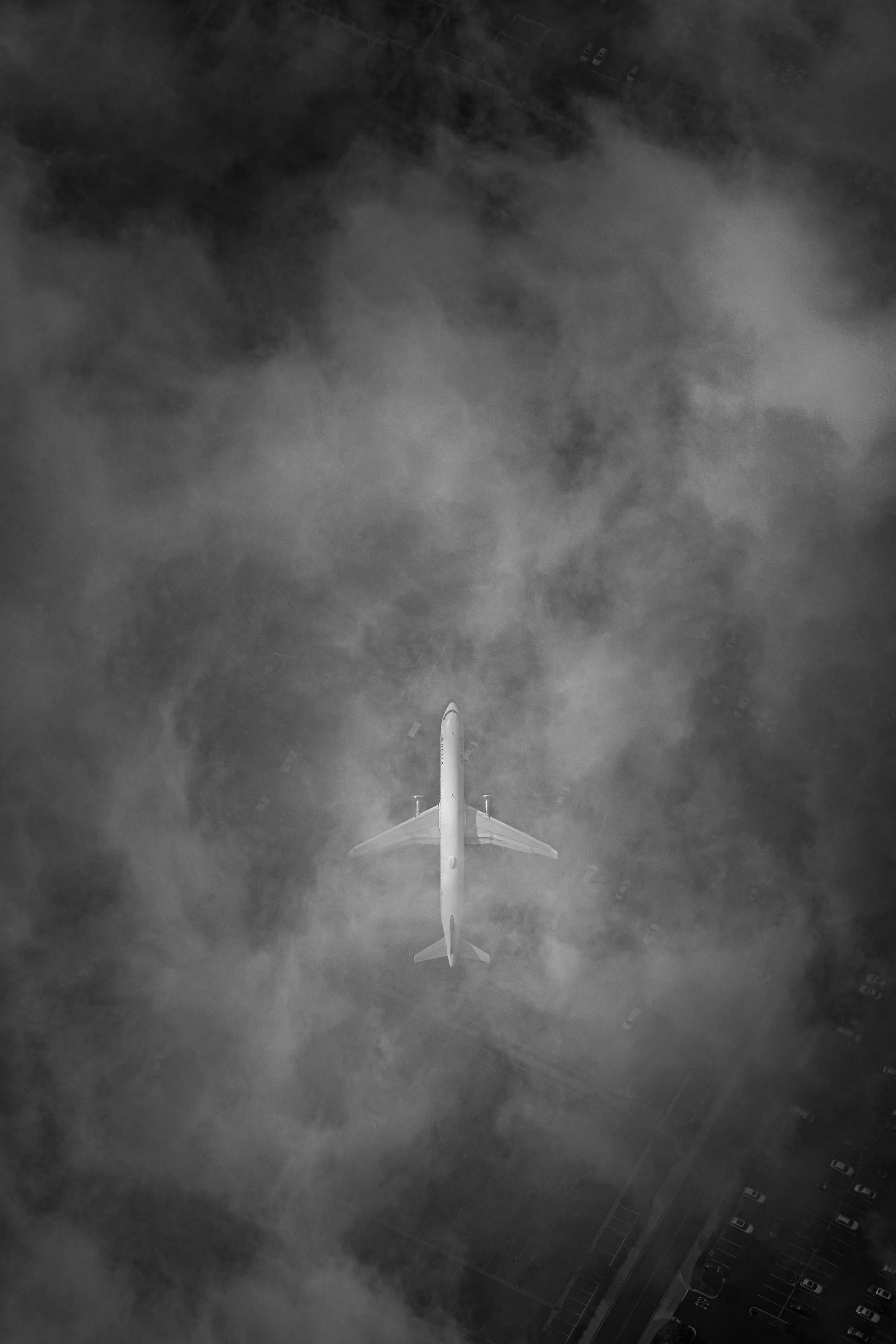 an airplane is flying through the clouds in black and white