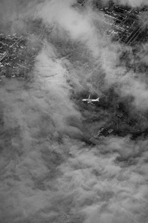 a black and white photo of a plane in the clouds