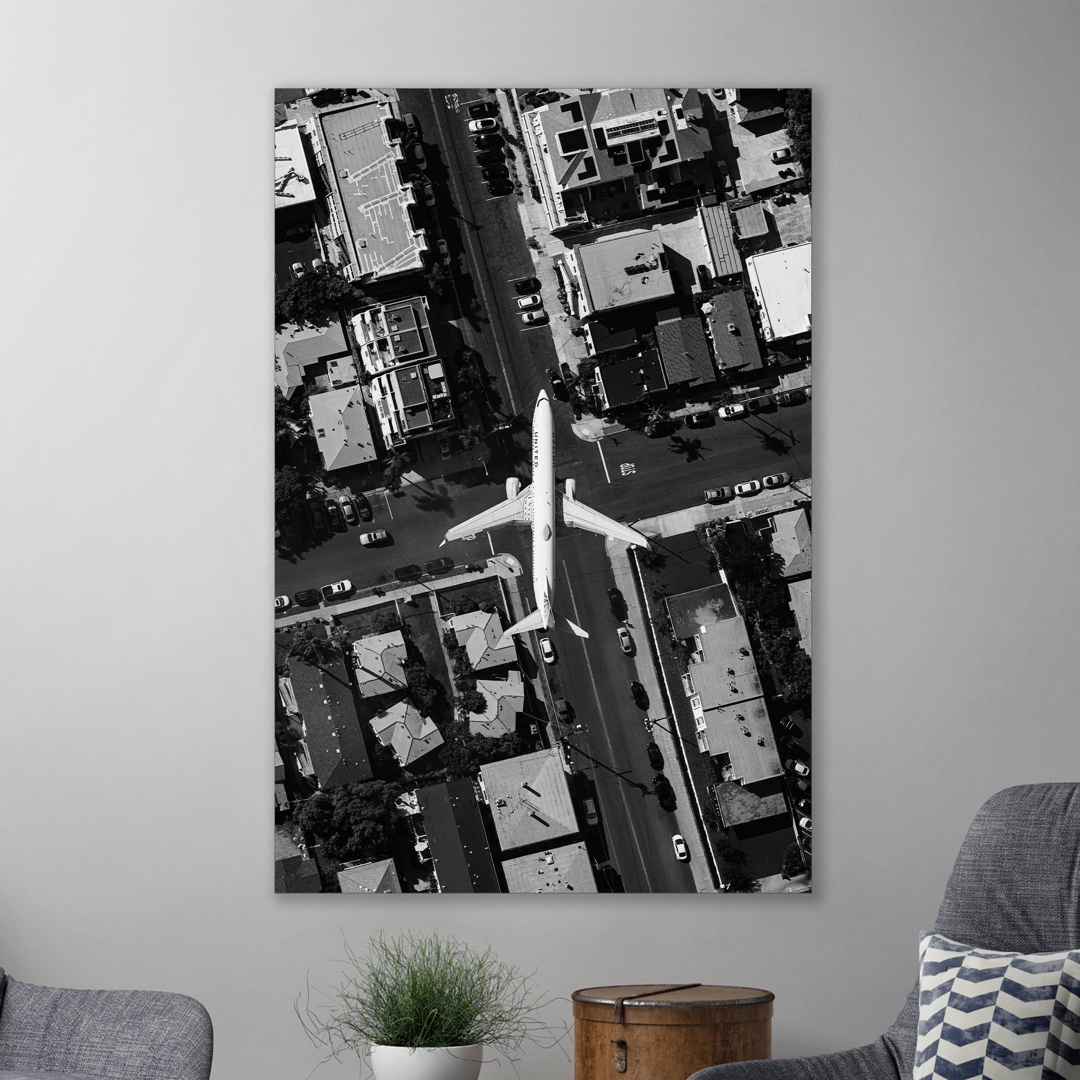 a black and white photo of an airplane flying over a city