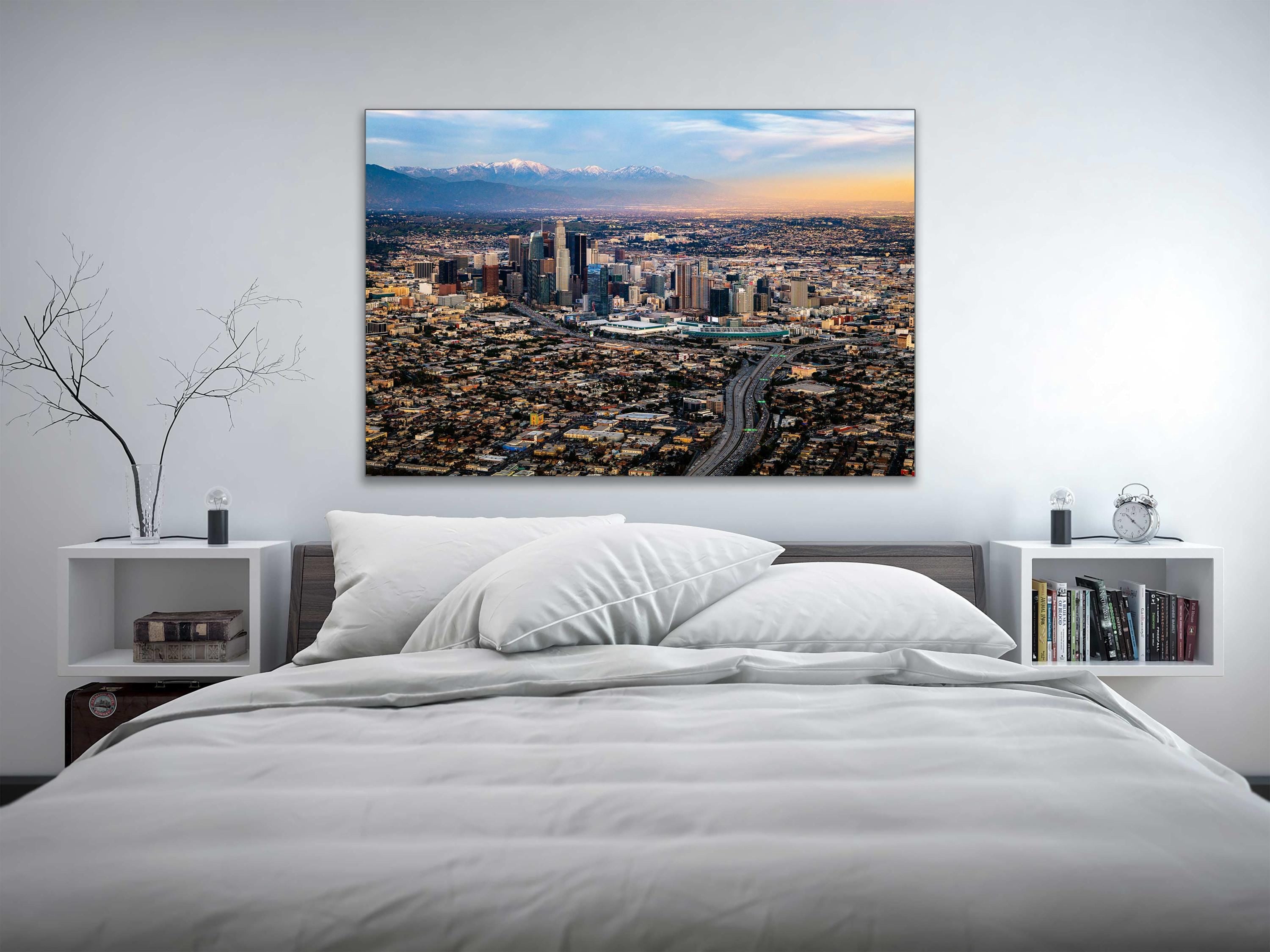 a bed with a white comforter and a painting on the wall above it