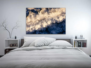 a bed with a white comforter and a painting on the wall