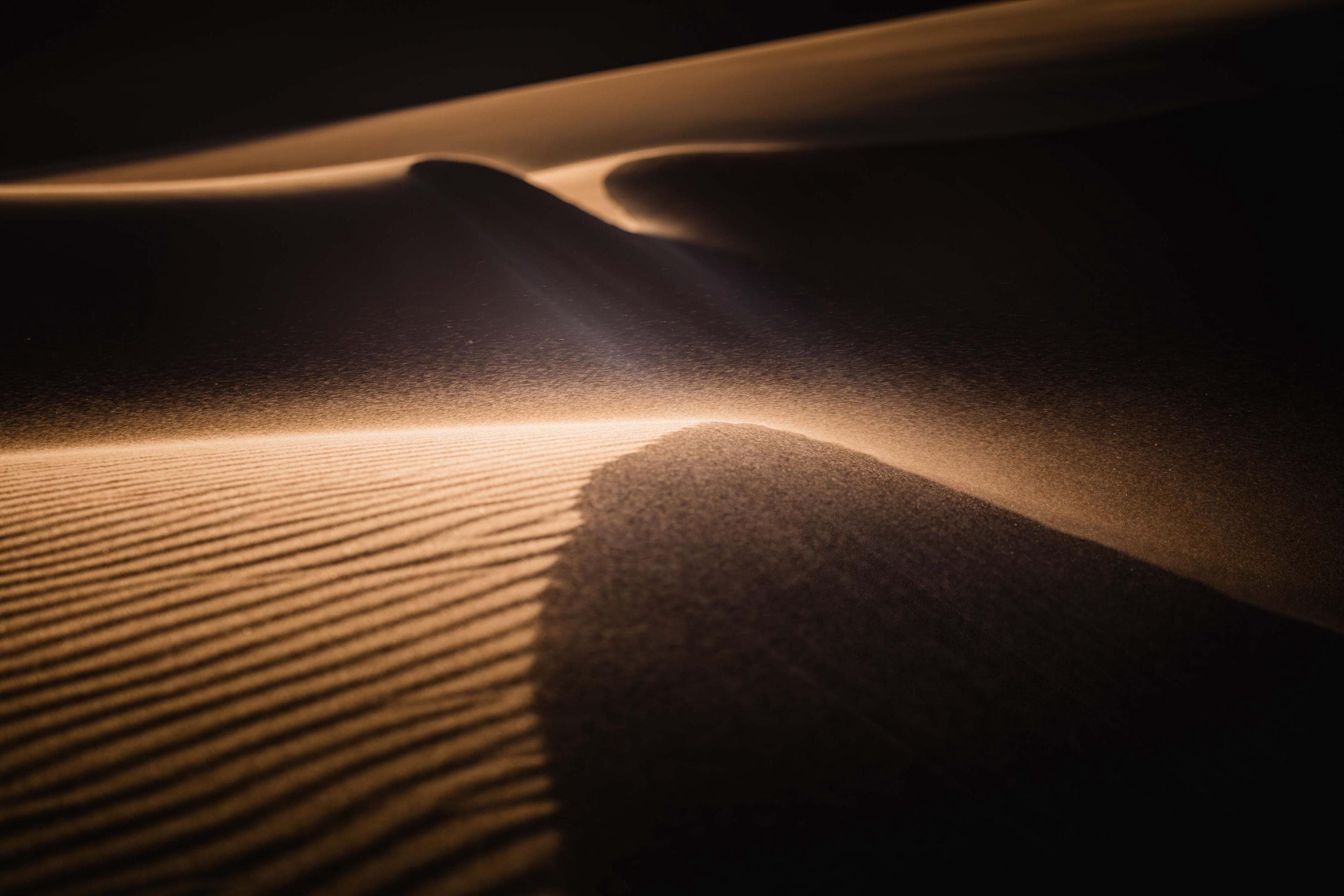 a shadow of a person standing on a sand dune