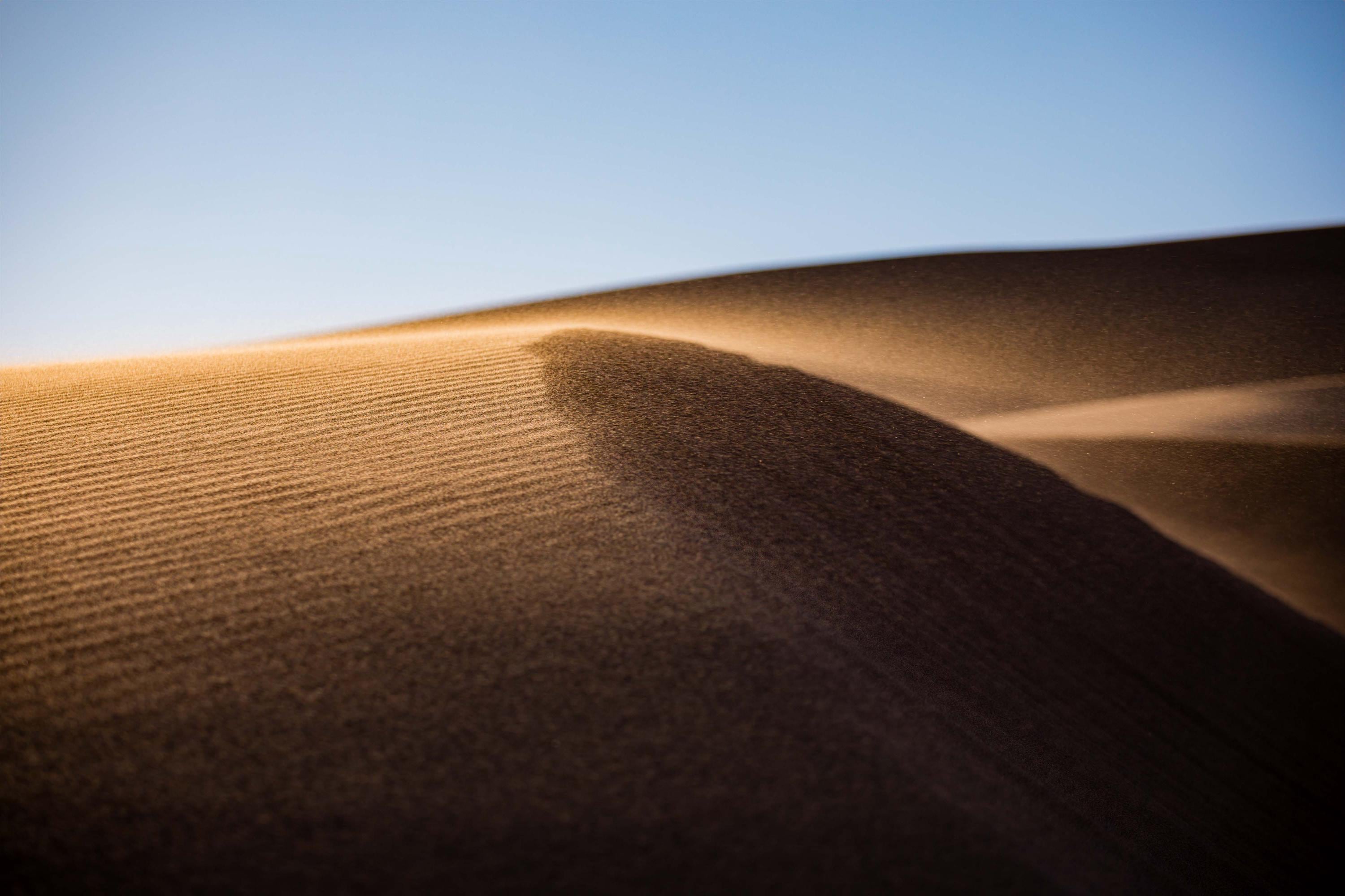 a sand dune with a blue sky in the background