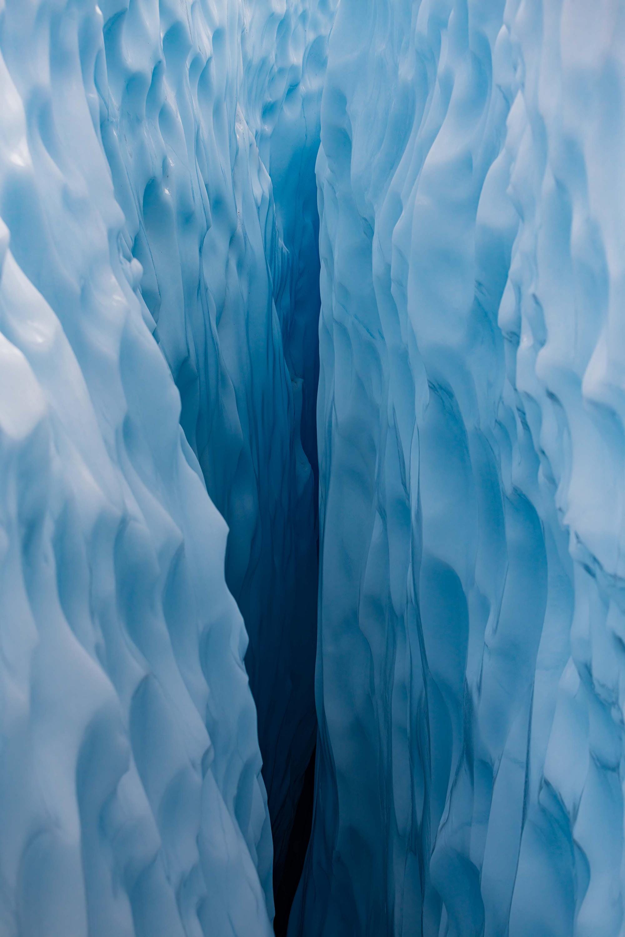 a large blue ice cave with water coming out of it